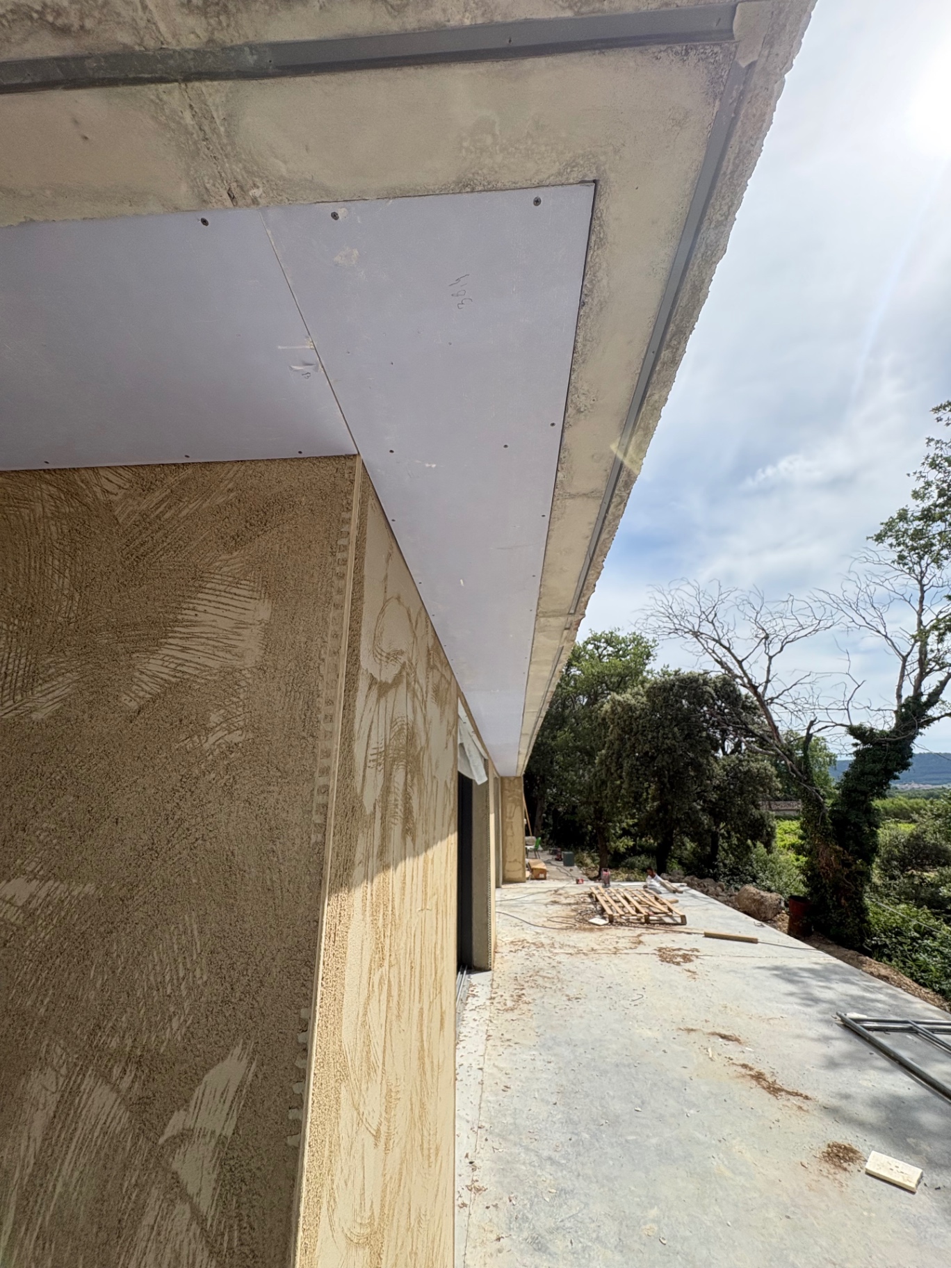 Plaquage en sous-face de débord de toit sur villa avec enduit ocre